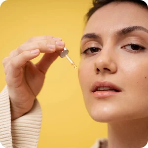 Mujer aplicándose serum de vitamina C en el rostro